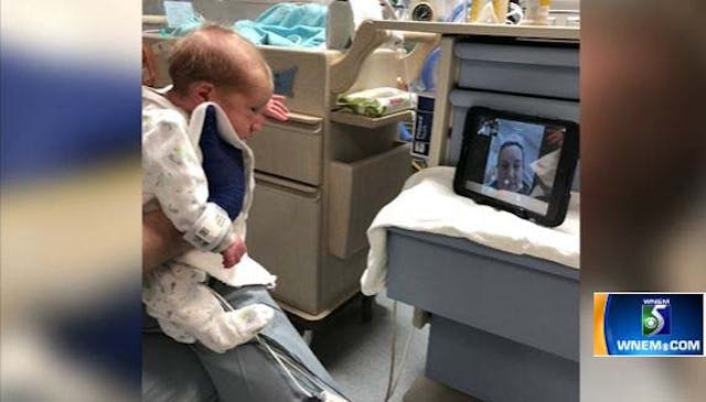 A nurse holds up one of the twins for Jen to see on video. Screenshot WNEM. screenshot, covid-19, twins, premature