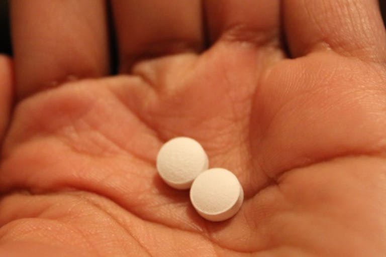 A hand holding two pills.