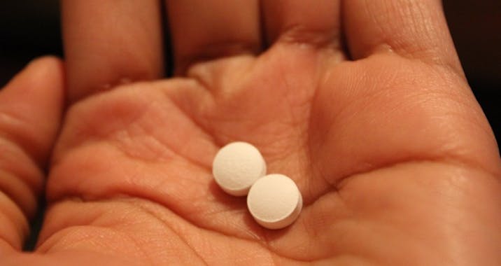 A hand holding two pills.