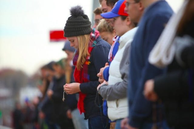 Shield of Roses president Elizabeth Eller, a junior majoring in History, prays the rosary at the fall Mega Shield (Photo courtesy Christendom College) Despite opposition, students from this college pray in ‘mega shields’ at abortion facility image