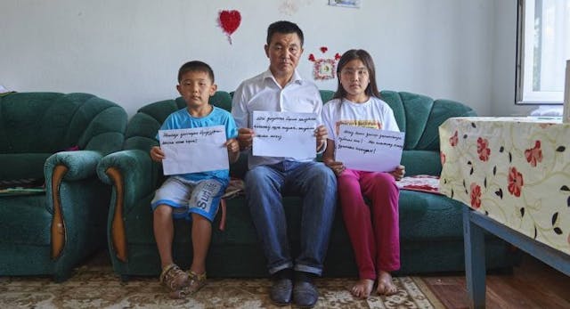BAIDIBEK, KAZAKHSTAN – JULY 27, 2018: Uali Islam and his two children, hold signs calling for the release of his wife, Sayragul Sauytbay, who fled China after being forced to work in a internment camp in China’s far north west. On Aug. 1, a court ruled she will be reunited with her family, not deported back to China. (Photo by Izturgan Aldauev/For The Washington Post via Getty Images)