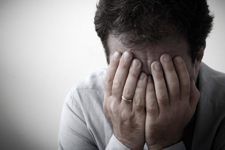 Close-Up Of Mature Man With Head In Hands Against White Background