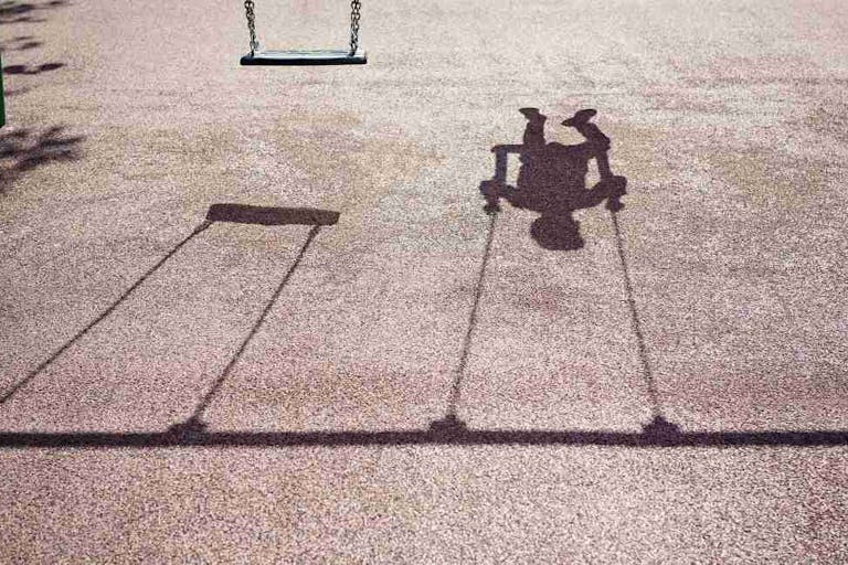 Shadow of a child on a playground swing