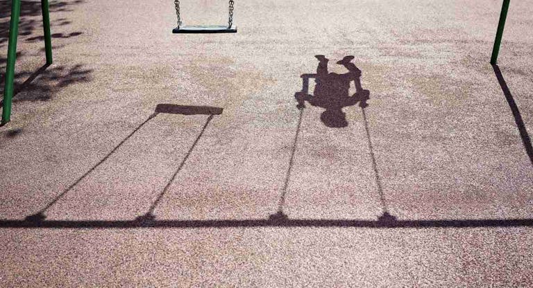 Shadow of a child on a playground swing