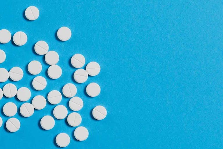 White pills scattered on a blue background.