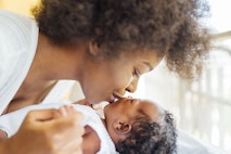 African-American mother kisses newborn baby