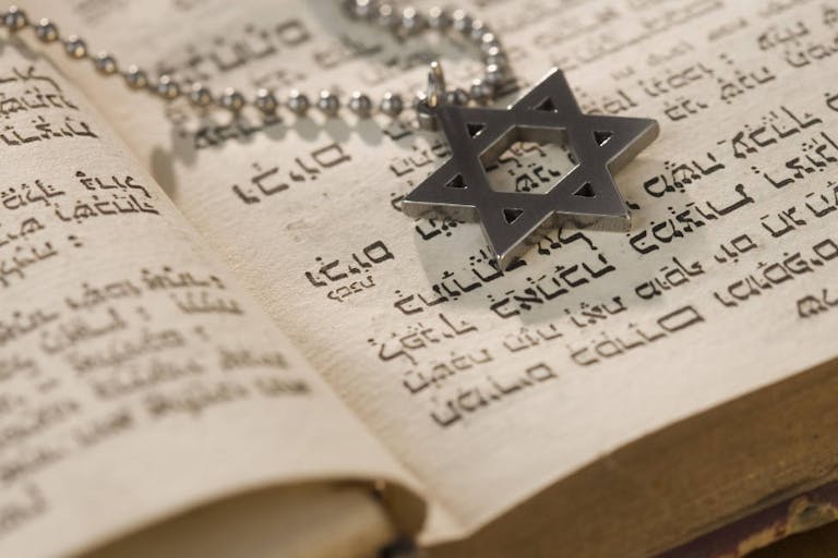 Star of David necklace on book with Hebrew text