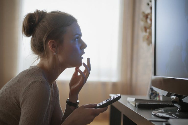 young woman looking in suspense at tv