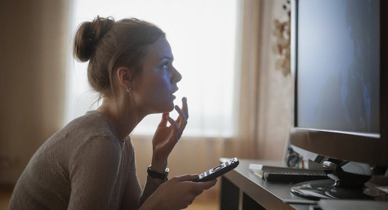young woman looking in suspense at tv