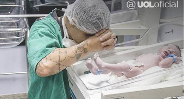 Man kneels in prayer by newborn son