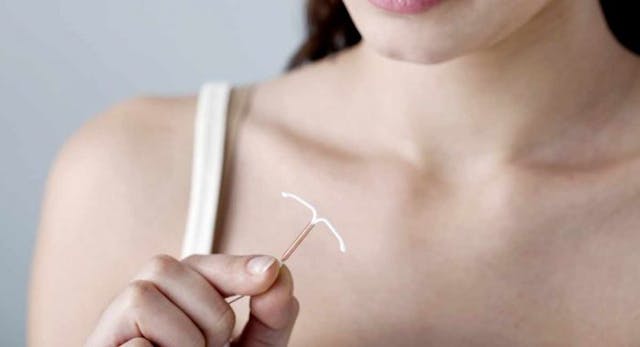 Woman holding an IUD device.