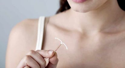 Woman holding an IUD device.