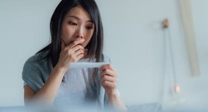 woman looks at pregnancy test in surprise