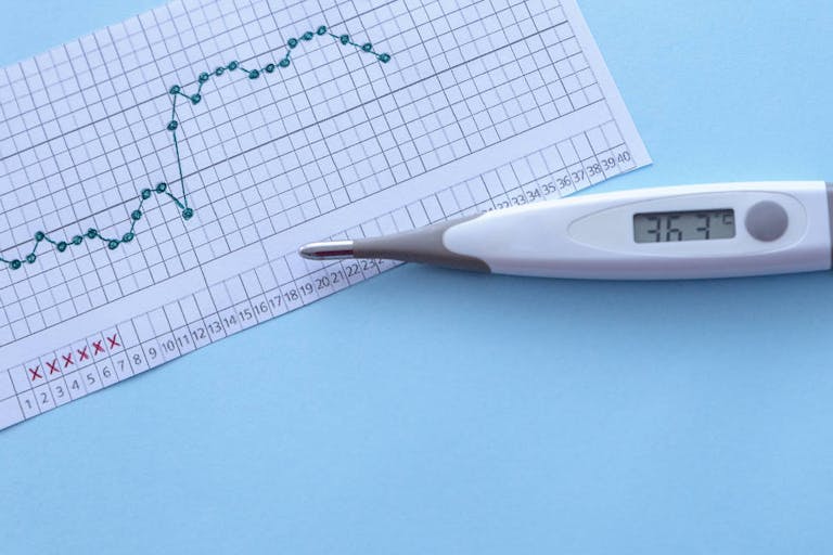 Pregnancy planning. Measurement of basal body temperature. Thermometer, temperature graph on a blue background. Copy space