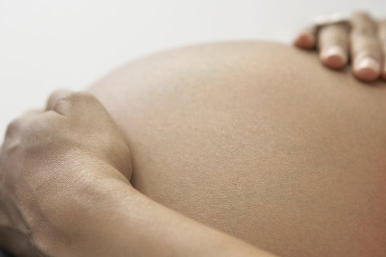 Close up of pregnant African woman’s hands on bare belly
