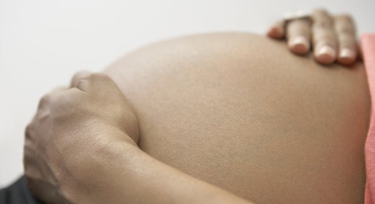 Close up of pregnant African woman’s hands on bare belly