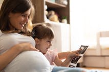Photo: mdphoto16/Getty Images pregnant mother and young daughter look at ultrasound photos