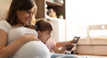 pregnant mother and young daughter look at ultrasound photos