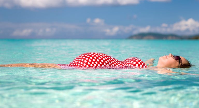 pregnant woman floating on water at the Caribbean beach