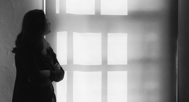 Thoughtful Woman With Arms Crossed Looking At Wall