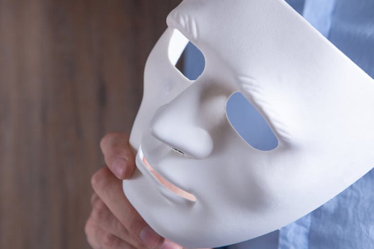 Businessman holding white mask in his hand