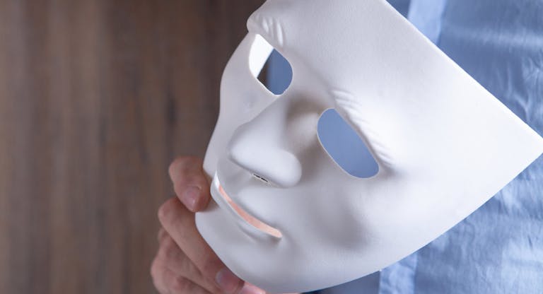 Businessman holding white mask in his hand
