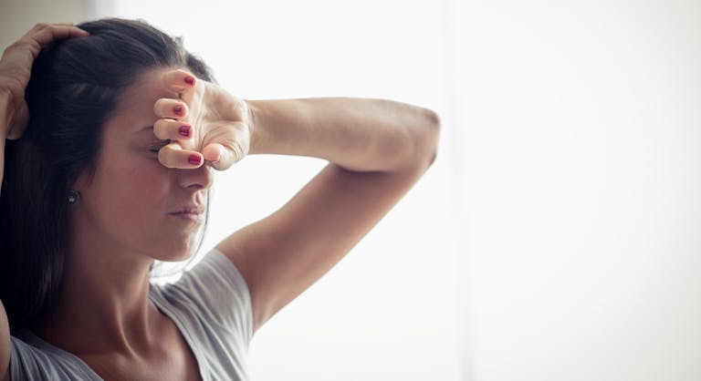 Young woman holding one hand on forehead