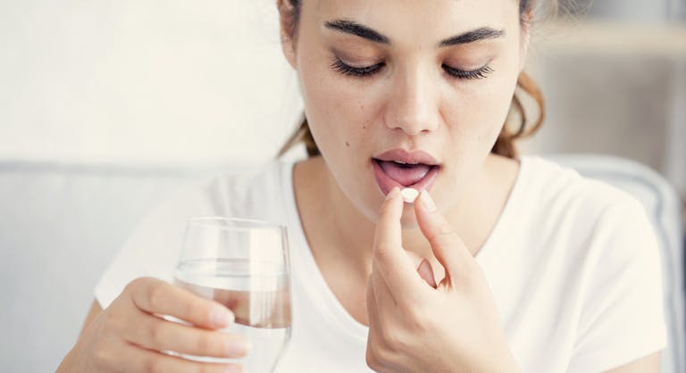 Young woman taking pill