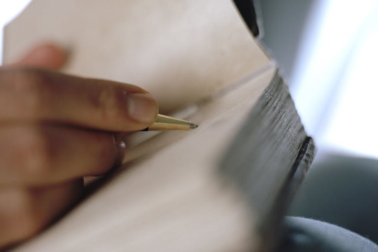 Woman’s hand writing on journal (focus on pen)