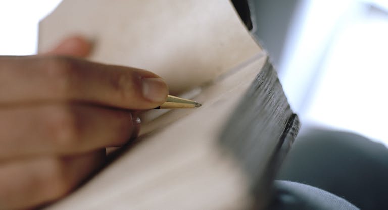 Woman’s hand writing on journal (focus on pen)