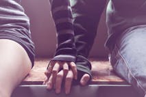 Getty Images A man and woman sit on a bench holding hands.