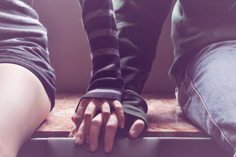 Getty Images A man and woman sit on a bench holding hands.
