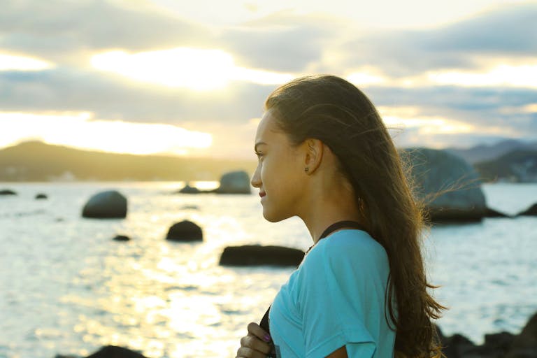 Girl contemplating sunset over the sea.