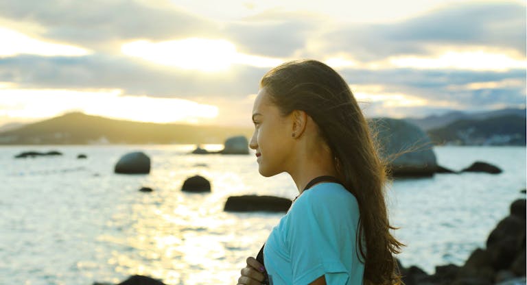 Girl contemplating sunset over the sea.