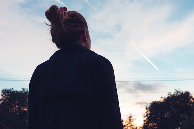 The silhouette of a young woman looking at sunset