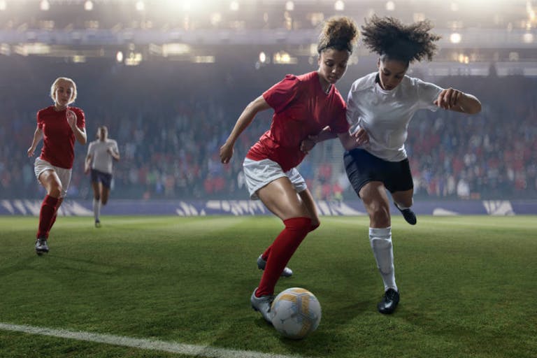 Professional Women Soccer Player Dribbling Ball Past Rival During Match