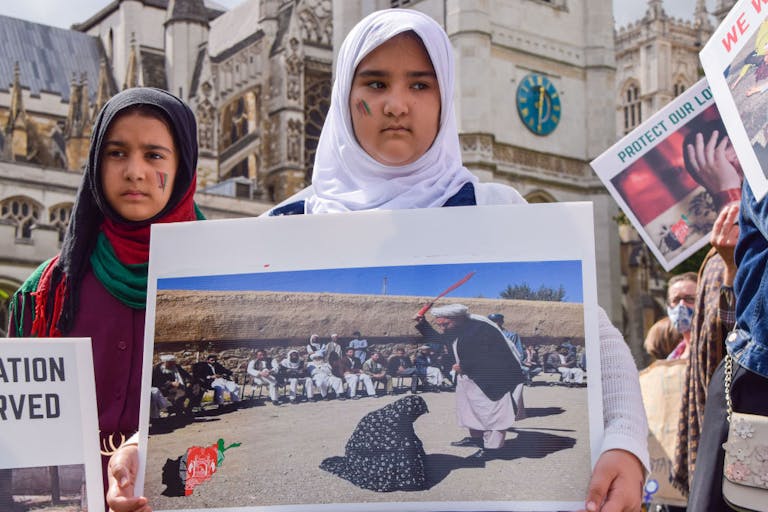 A young girl holds a picture of a woman being publicly