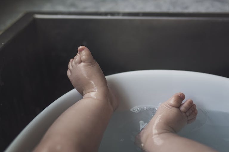 Low section of wet baby boy lying in bathtub at home