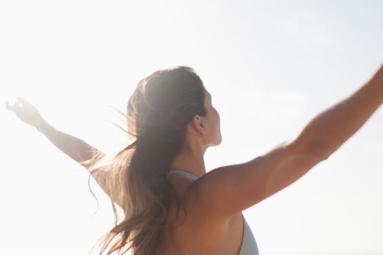 Woman standing with arms outstretched on beach