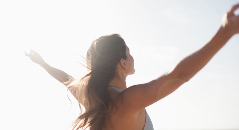 Woman standing with arms outstretched on beach