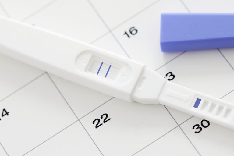 Pregnancy test showing positive result and calendar