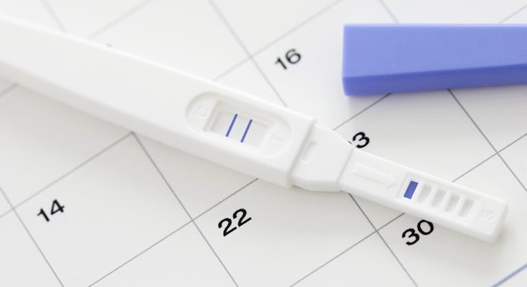 Pregnancy test showing positive result and calendar