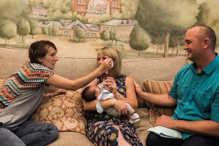 Birth mom wipes the tears of adoptive mom. Copyright Sara Liz Photography.