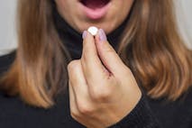 Photo: Andrii Zorii/Getty Images Young woman taking a pill. A woman takes medicine antidepressant or birth control pill, female puts tablet in mouth have painkiller or antibiotic. Healthcare concept with medicines.