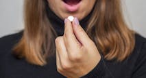 Young woman taking a pill. A woman takes medicine antidepressant or birth control pill, female puts tablet in mouth have painkiller or antibiotic. Healthcare concept with medicines.