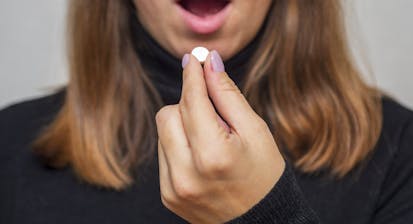 Young woman taking a pill. A woman takes medicine antidepressant or birth control pill, female puts tablet in mouth have painkiller or antibiotic. Healthcare concept with medicines.