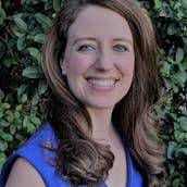 Stephanie Gray Connors headshot in front of green bushes