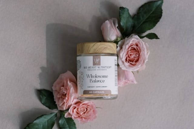 Pink flowers around a jar of supplements