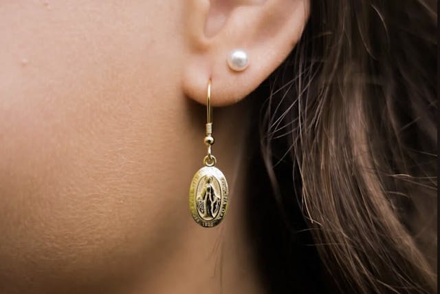 A pearl earring and a gold earring with a saint on it