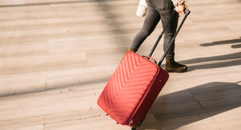 A woman pulling a pink suitcase